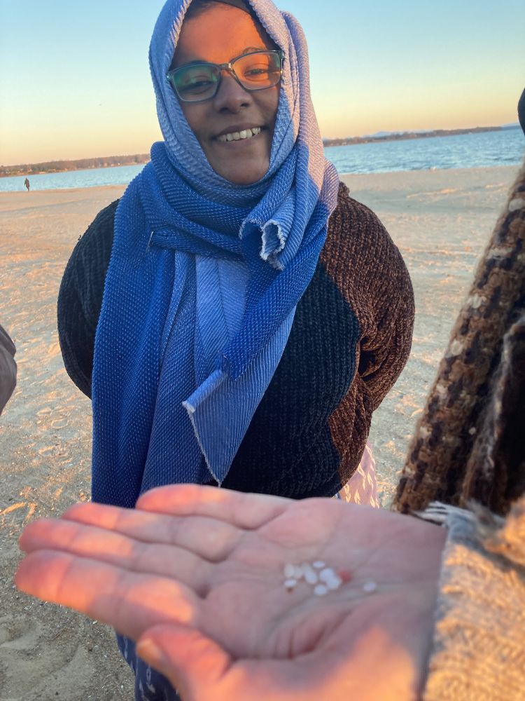 Plastic pellets in someone's hand and a smiling woman in a hijab. 