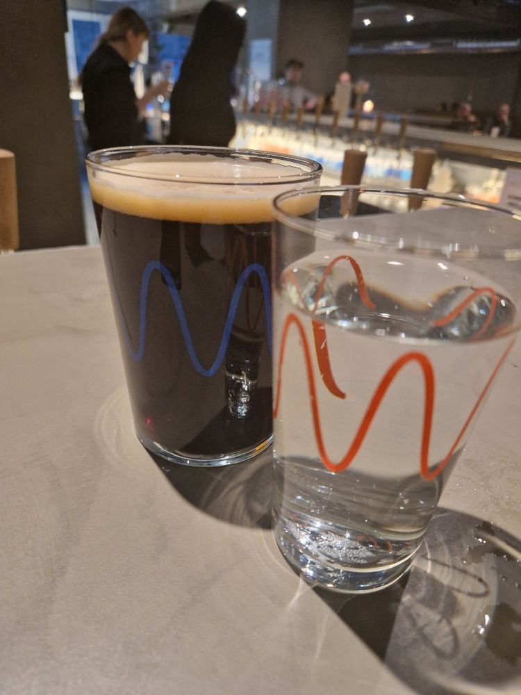 Glass of water in front of glass of porter.