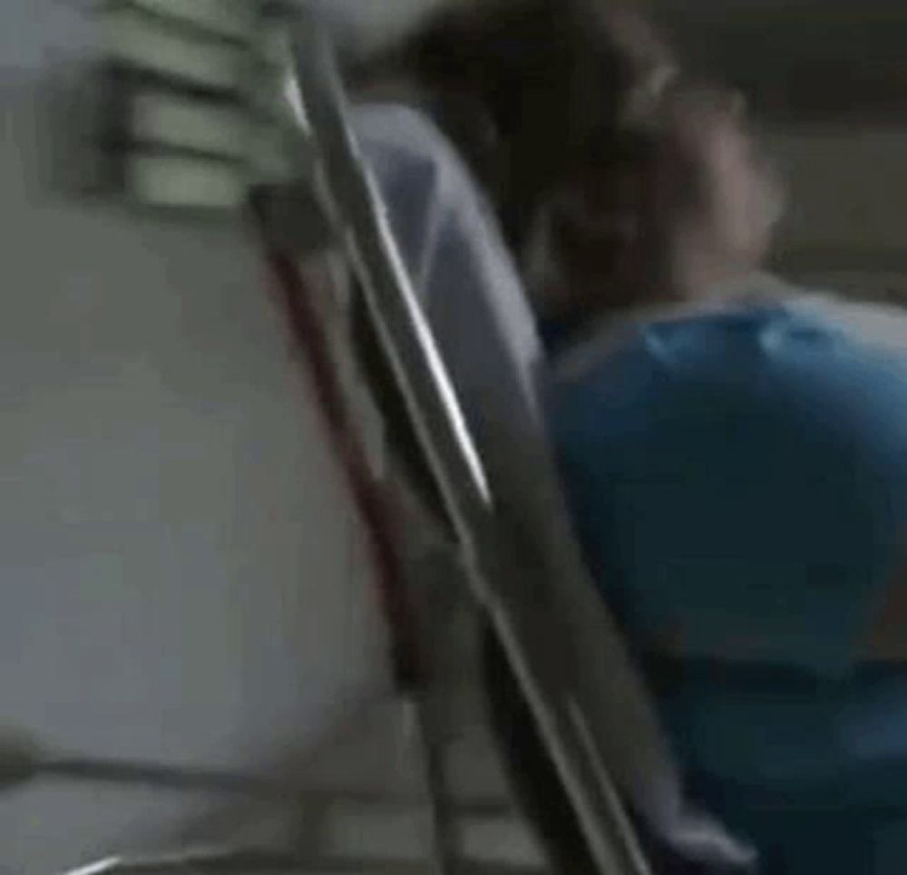 a woman in a blue shirt is laying in an ambulance while a man stands behind her .