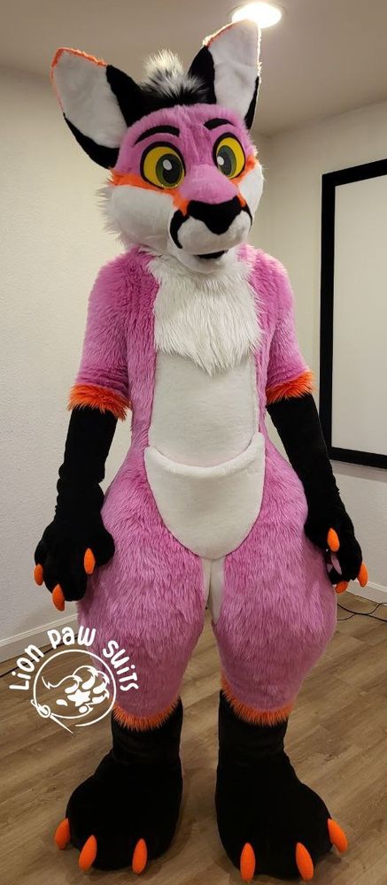 A pink and white kangaroo fursuit with black and orange markings.