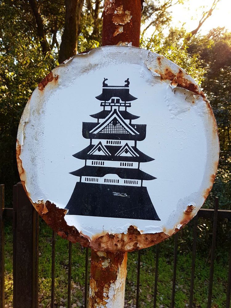 A rusted sign with an image of Fushimi Momoyama Castle