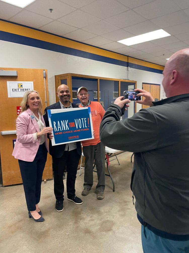 Koski, Eliott Payne, and a Fairvote volunteer have their photo taken by DFL Chair Richard Carlbom