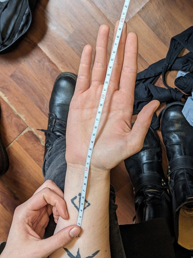 A butch's hand with a tape measure laid out from a defined point on the wrist, to indicate depth.