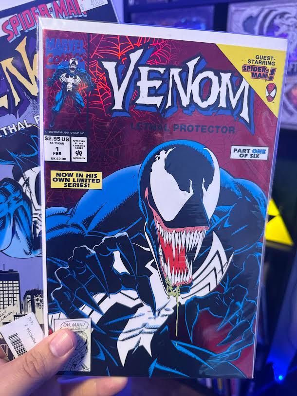 Venom, the Lethal Protector foil comic book on a stack of other comics. 