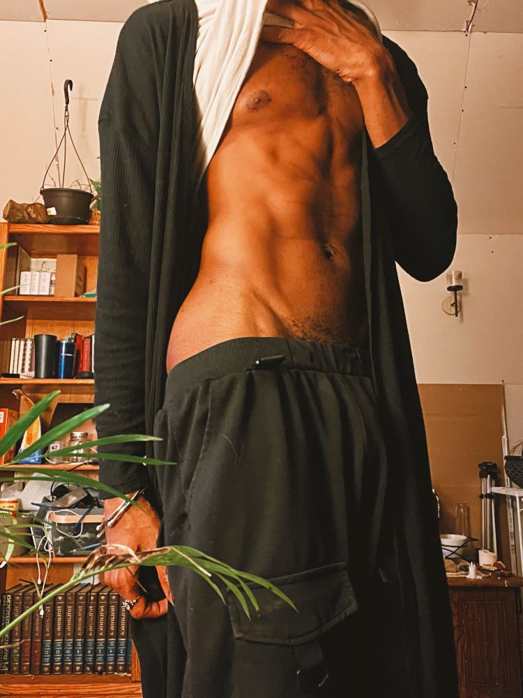 Darling teasingly lifts their shirt to expose their bare, toned torso.