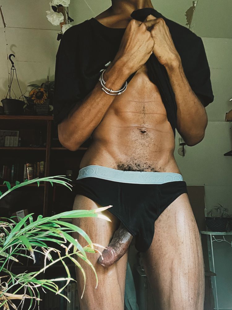 Darling meekly holds their shirt up so show their stomach and black underwear while their erect cock hands from the leg opening.-