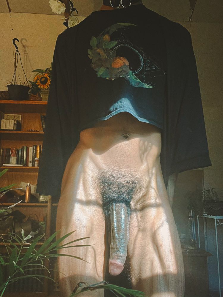 Darling stands in a black crop top and robe. Their veiny cock rests between two muscular legs.