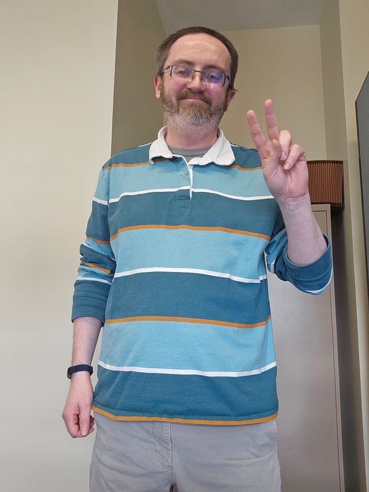 Its me with a big grin and flashing the peace sign.  Got on a green striped polo shirt.