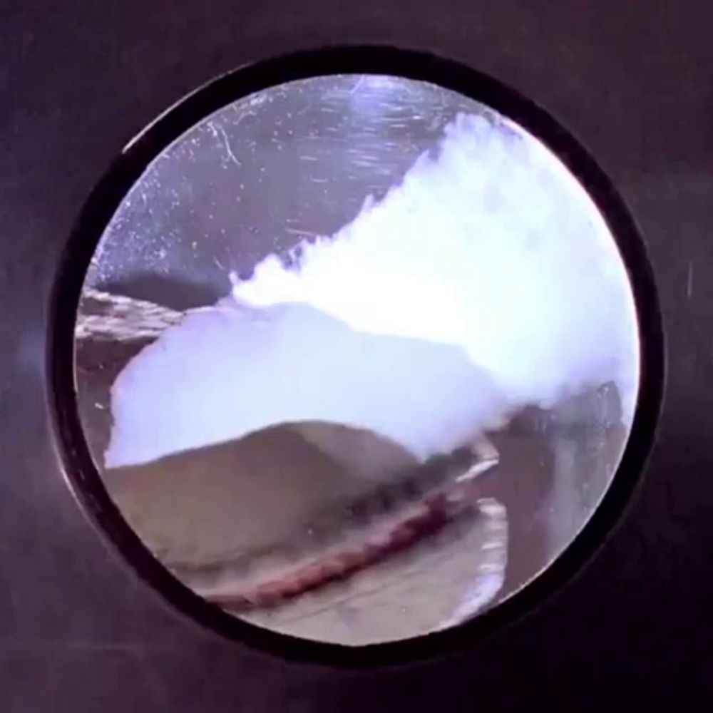 a close up of a circular object with a reflection of a wave