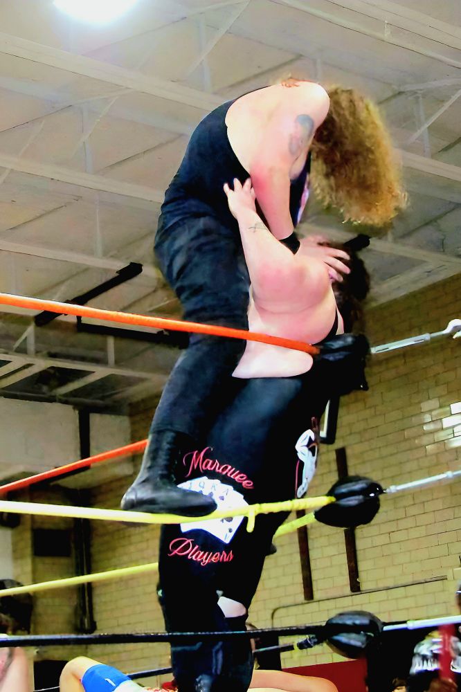 Professional wrestler Hannibal Rex standing over Big Jake Shephard in the corner turn turnbuckle. Rex is gouging Jake's eyes out. 