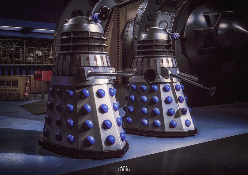 CG image. Two Daleks standing in a recreation of the Laboratory set from The Power of the Daleks