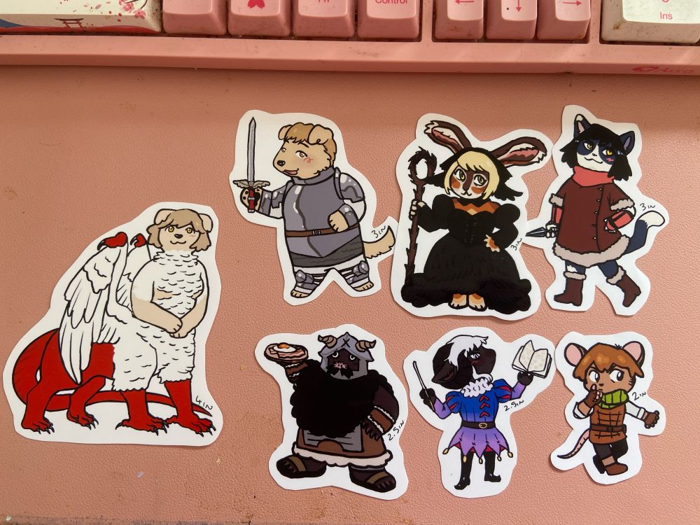 a photograph of drawings of the main cast of dungeon meshi as anthropomorphic animal people cut out and labelled with their size in inches. they range from chilchuck at two inches tall to falin at four inches tall. 