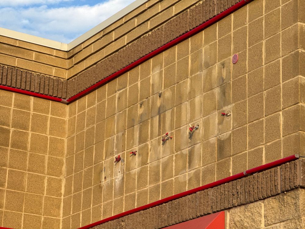 A brick facade with the remnants of an Arby’s sign that has been removed. (The registered trademark symbol remains for some reason.)