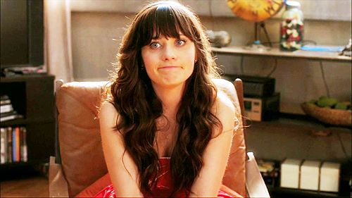 Jessica Day from New Girl (played by Zooey Deschanel) making an awkward face while sitting in a leather chair