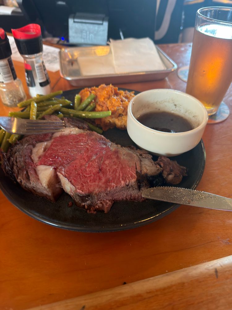 A plate featuring a prime rib that was advertised as 12oz but might be bigger, garlic green beans, and mashed sweet potatoes 