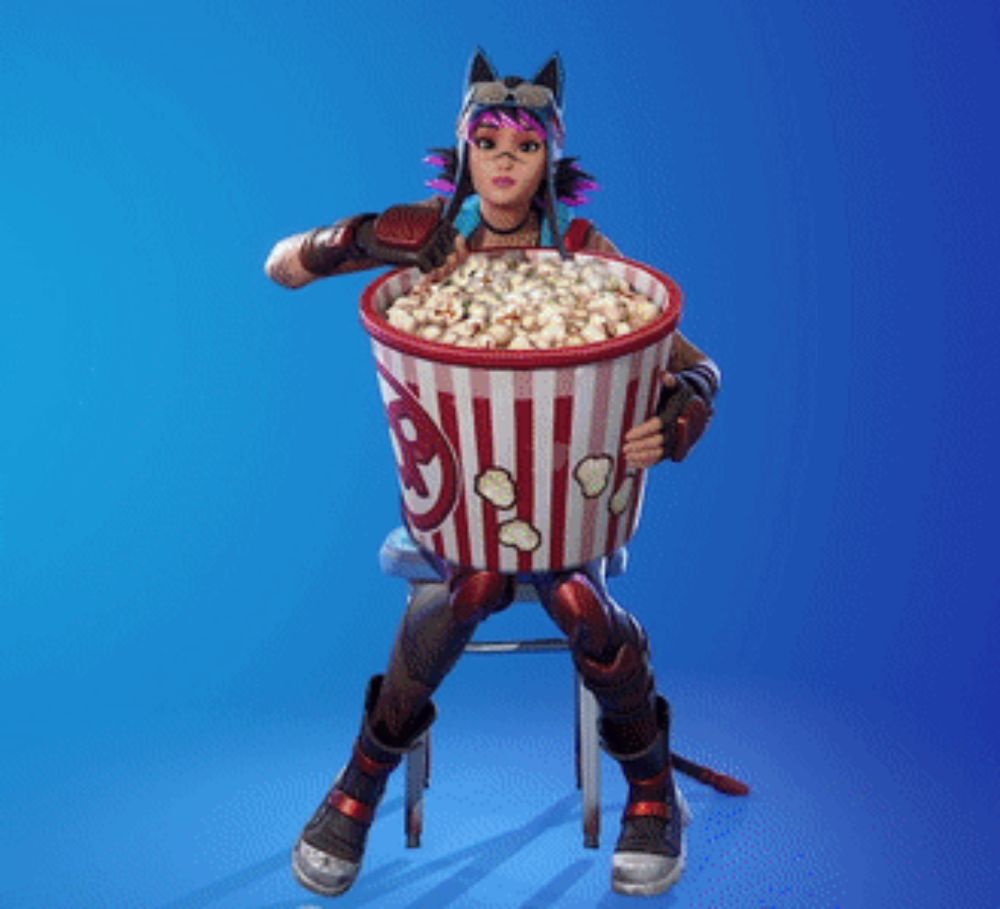 a woman is sitting on a stool holding a large bucket of popcorn