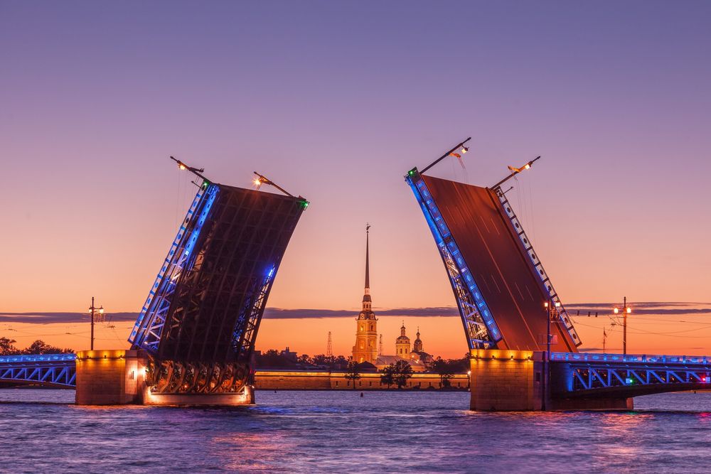 An evening picture of a St. Petersburg drawbridge cast in light orange and purple hues of the sunset.