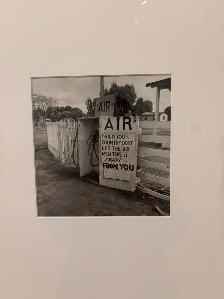 Dorothea Lange photo of a sign from 1940s that reads "This is your country don't let the big men take it away from you"