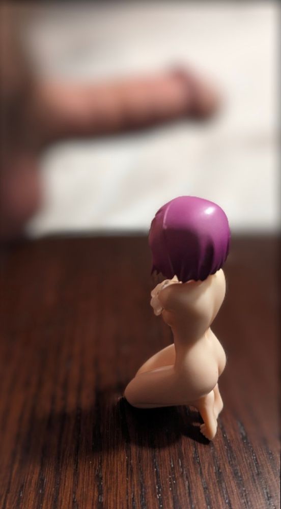 A naked anime figure with a huge blurred cock in the background.