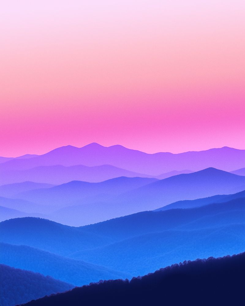 A photo of a mountain range at sunset. The sky is a vibrant pink and purple, and the mountains are layered in shades of blue and purple.