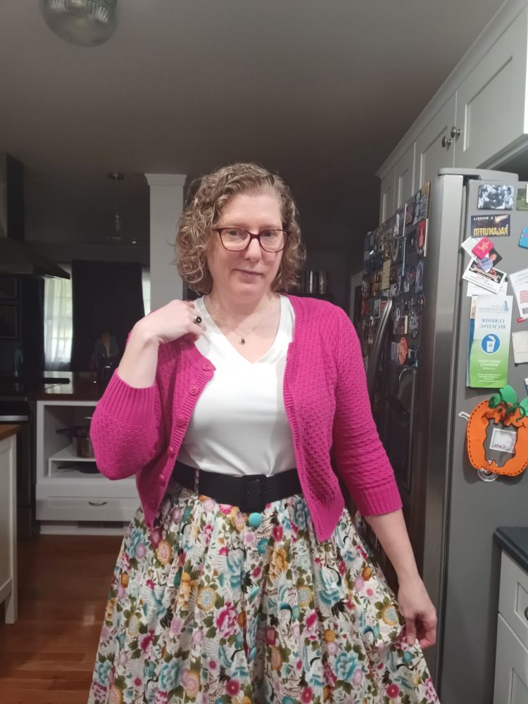 Me, in a hot pink cardigan, white top, and floral skirt.