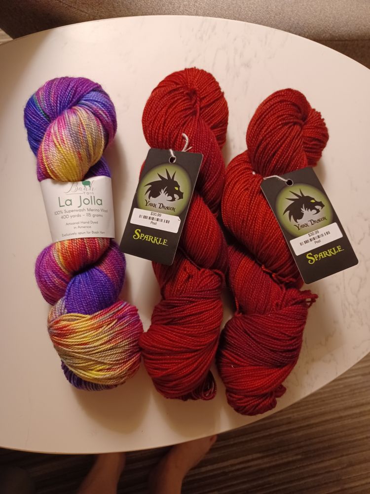 One skein of "market blooms" and two of a ruby colored sparkle, both superwash in fingering weight.