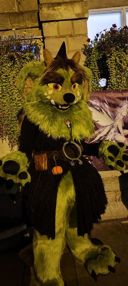 fluffy troll in a long black cardigan outside at night by a town hall looking quite excellent
