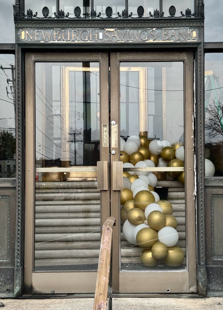 Steps inside a closed building with gold and white balloons ascending up the staircase 