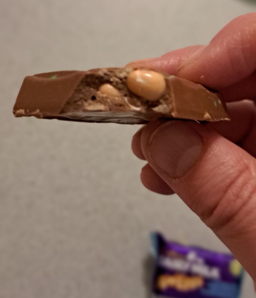 Hand holding a chocolate with a bite out of it, revealing the MiniEggs within the DairyMilk.