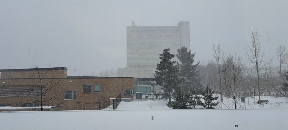 Laurentian University (Cliff Fielding Building in the foregroune, Parker Building in the background) with snow falling and accumulating on April 7, 2025
