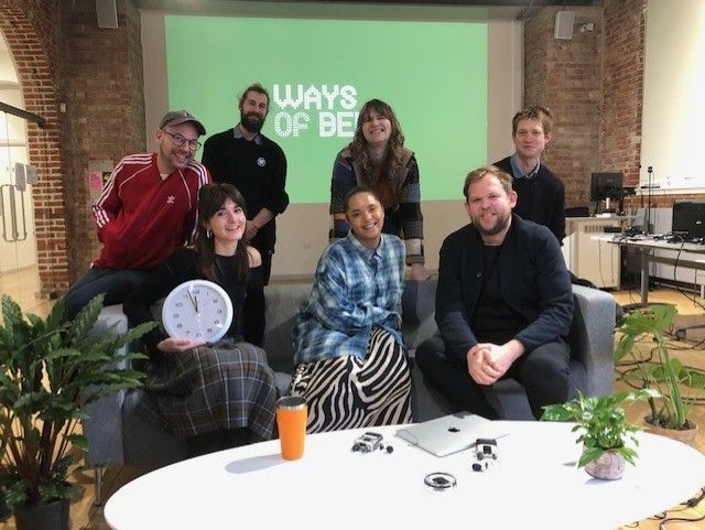 Seven people sitting on and behind a daytime-tv style sofa, smiling