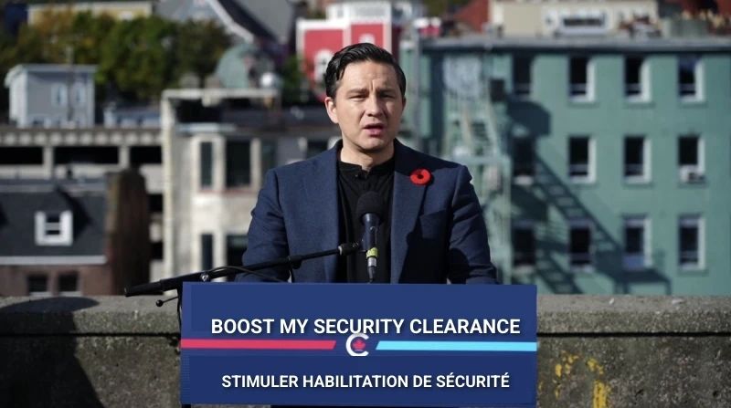 Pierre Polievre making an announcement. The placard in front says "Boost my security clearance". Satire