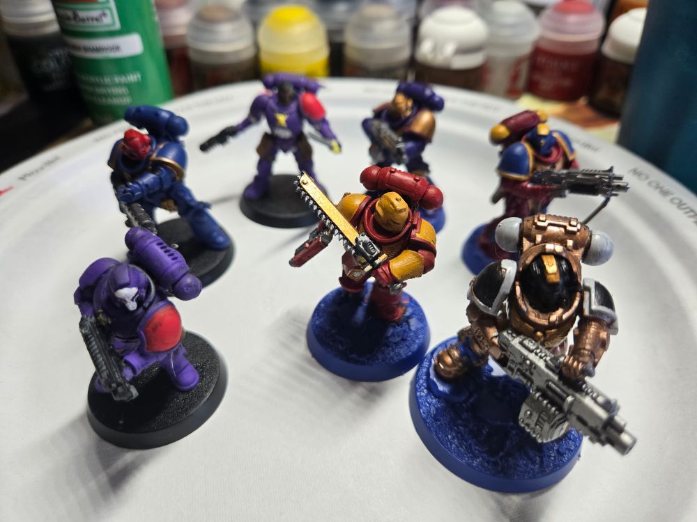 Numerous Space Marines painted with different colors and styles showcasing a new painter artist to the hobby. 