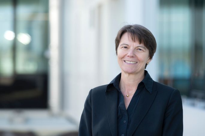 Claudia Eckert steht vor einem Gebäude und blickt lächelnd in die Kamera.