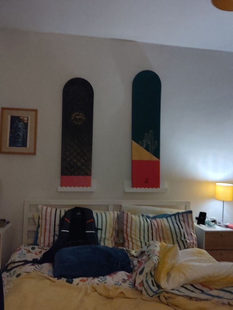 two wooden body boards hung on wall with bed underneath 