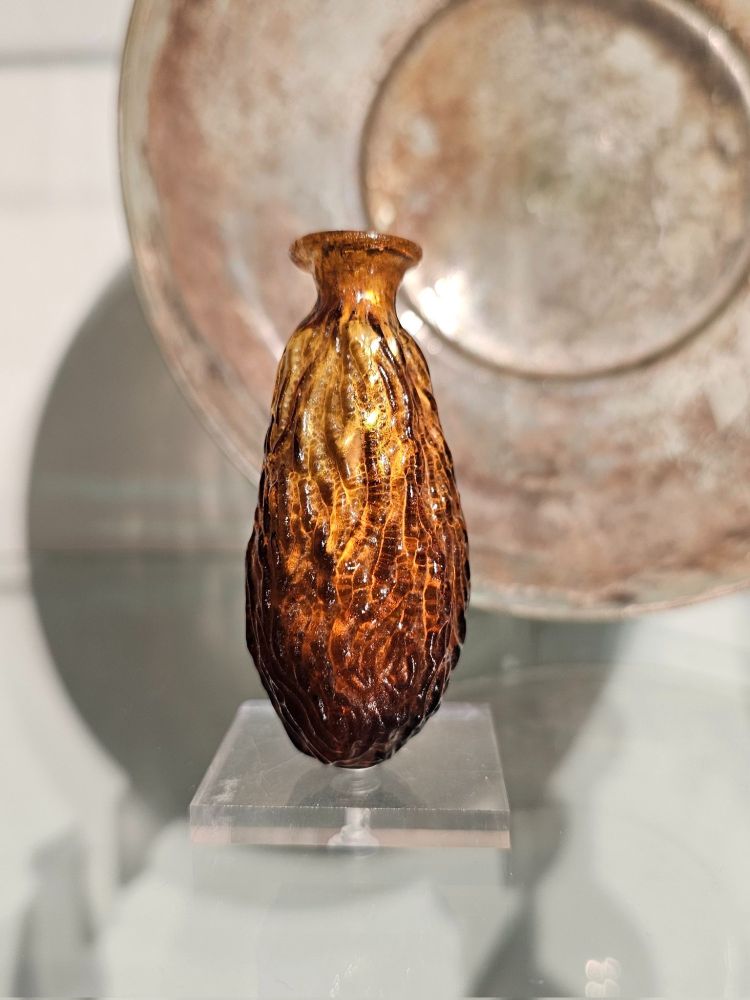 A close-up of a small, brown glass bottle, shaped like a dried date.
