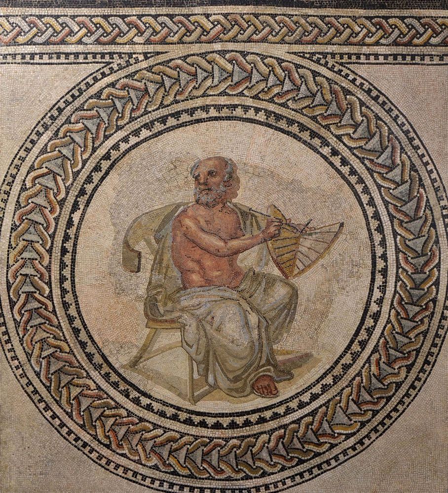 Mosaic depicting a seated, bearded man draped in a white robe, holding and examining a sundial. He is surrounded by a circular geometric border with intricate patterns.