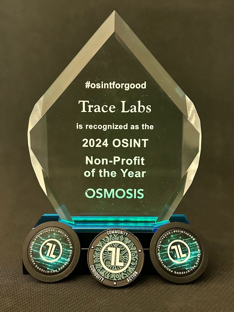 Crystal trophy that reads: #osintforgood TraceLabs is recognized as the 2024 OSINT Non-Profit of the Year  OSMOSIS.
Below the trophy at the base are two TraceLabs poker chips, with the TraceLabs challenge coin in between them. Challenge coin has the TL logo and the words “Community, Curiosity, Action”