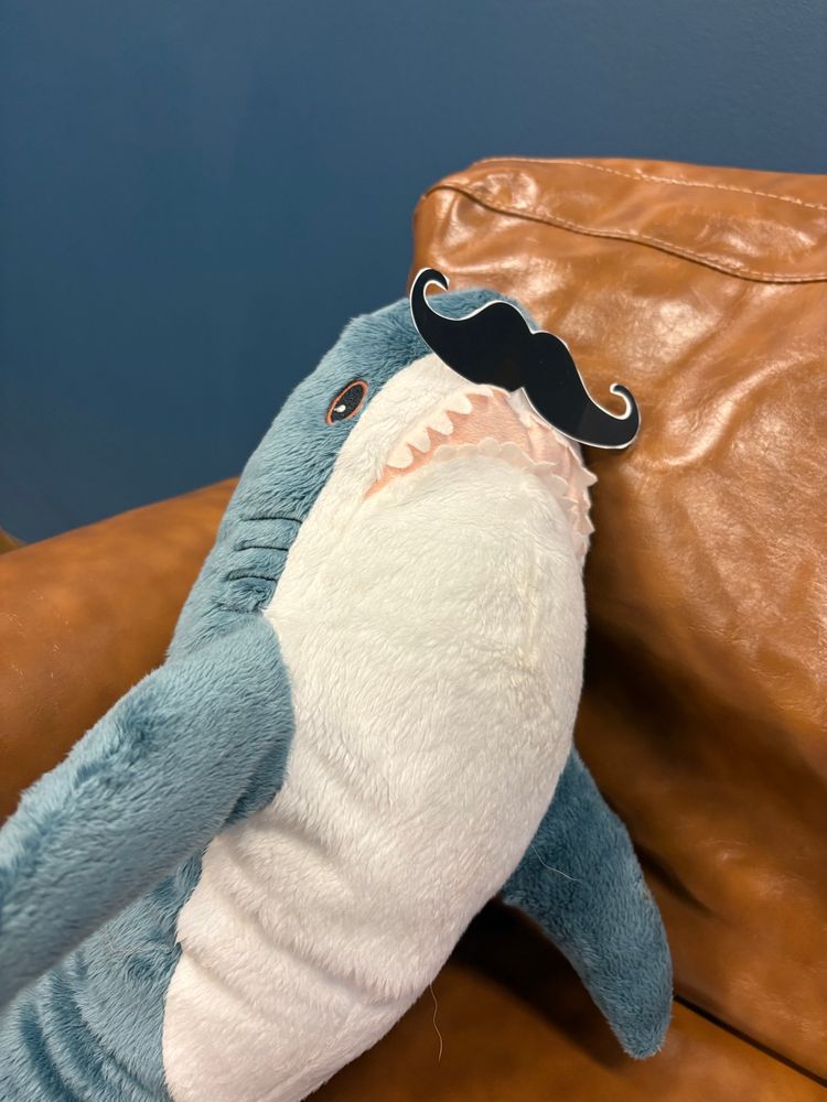 Mustached tiny shark lounging on a couch.
