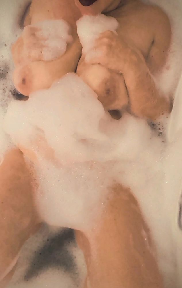 Poly lays in a bubbly bath with her shoulders, tits, and legs out of the suds. The tiniest hint of her red lipstick is at the top of the frame before her face gets cut off. This video really is so very hot. I hope I can get through it without walking off of the nearest pier.