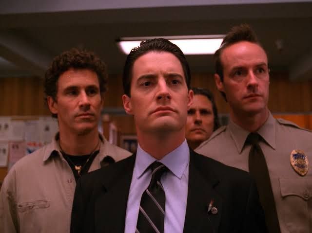 Cena da série Twin Peaks, primeira ou segunda temporada: na frente, o agente do FBI Dale Cooper, e atrás o xerife Truman e os policiais Andy e Hawk