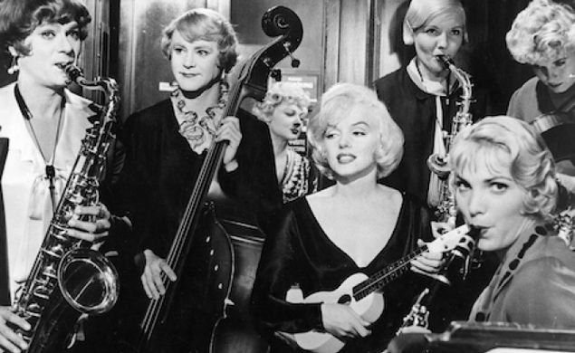 The main characters from "Some Like It Hot" Tony Curtis as Josephine (playing saxophone), Jack Lemmon as Daphne (playing the bass) and beside them sits Marilyn Monroe as Sugar and her co-band mates all playing different instruments.