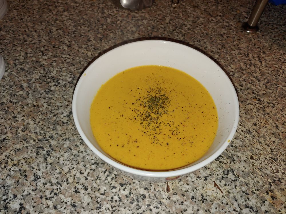 Pumpkin and goat cheese soup. A light orange/yellow color garnished with dill and black pepper. Recipe from the Zelda Twilight Princess cookbook.