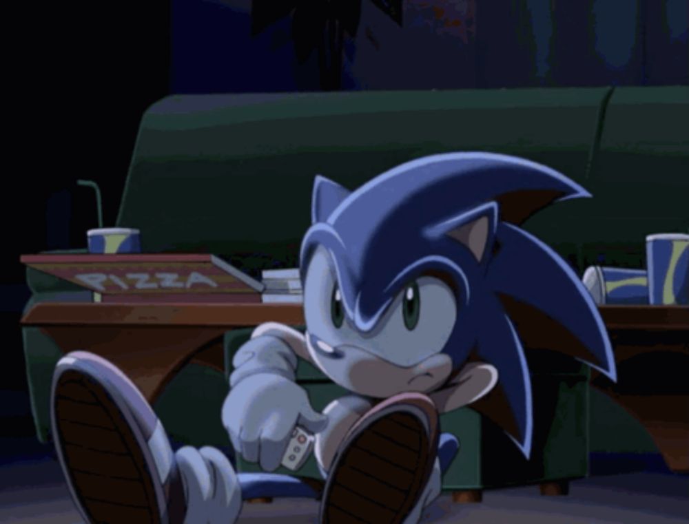 sonic the hedgehog sits on a couch with a pizza box on the table