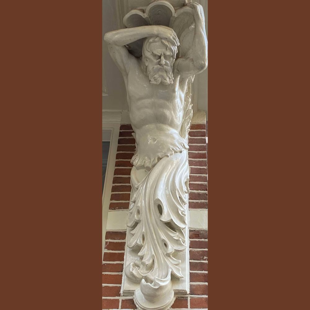 Bakstenen muur met witte mansfiguur die een afdak ondersteunt.