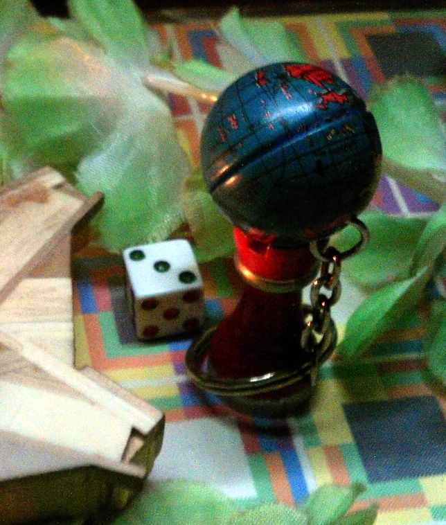 A red castle piece on a colorful grid wearing a globe keychain as a hat. Next to it, the dice says 3 on a black square.
