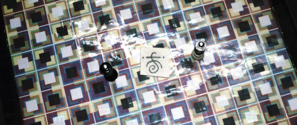 Two chess queens and a witch's sigil between them on a checkerboard.