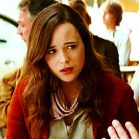 Ariadne from Inception, a young white woman with long wavy dark hair, wearing a red cardigan and a skeptical expression.