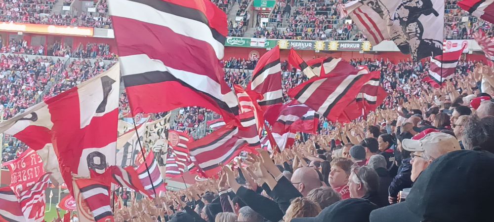Wehende Rote-weise Fahne und Klatschende Ultras
