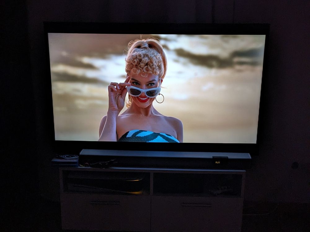 Foto des Films Barbie, bei der die Hauptdarstellerin mit leicht heruntergezogener Sonnenbrille lächelt.